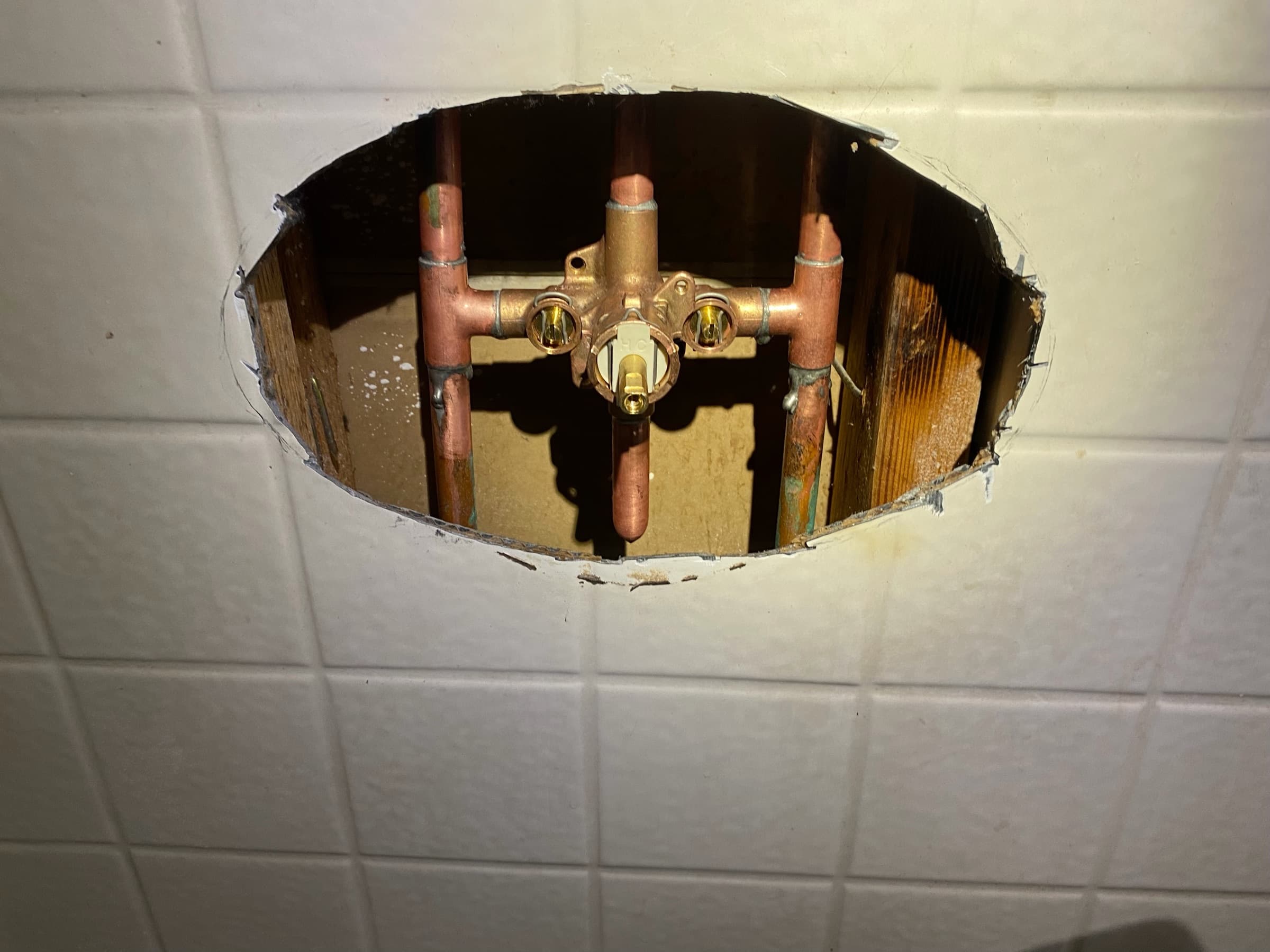 Copper shower supply lines and a brass pressure-balancing valve body exposed in an open wall cavity during a shower valve replacement